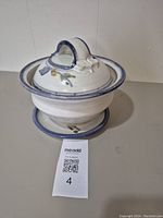 Full view of the pottery colander set with lid on base, showing floral decoration and blue rims.