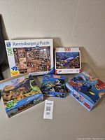 Five puzzles shown: two 500 piece Ravensburger jigsaw puzzles and three 3D puzzles with animated characters and ocean themes.