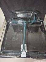 Top view of three clear glass Pyrex pans arranged on a dark surface showing the loaf pan on top and two rectangle pans below.