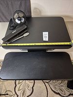 Top view of desktop riser surface showing items included and tape measure extended to show size.