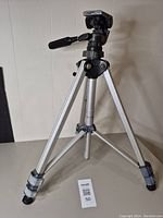 Full view of the Slik tripod standing with legs extended showing its aluminum body and pan tilt head with handle.