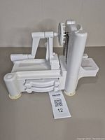 Side view of white plastic manual spiralizer dispenser with suction feet and crank handle