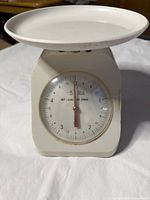 Front view of white analog kitchen scale showing dial and weighing tray