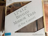 Four boxes of Monarch 12x12 inch bevelled mirror tiles, six tiles per box, unopened and stacked.