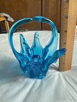 Blue blown art glass candy bowl with artistic sculptural form placed next to a ruler showing it is about 5 inches tall.