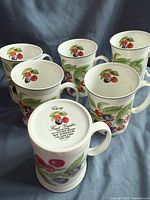Set of six tall bone china mugs with cherry fruit garden design on a dark backdrop.