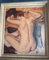 Framed print of nude woman combing hair by Edgar Degas in gold-toned frame.