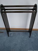 Front view of solid wood quilt/blanket holder showing two horizontal rails and curved side panels.