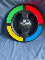 Photo of Simon Swipe electronic memory game showing circular unit with four colored segments and central speaker area