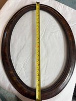 Full view of the oval wooden frame with a tape measure showing the height of approximately 24 inches