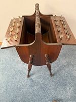 View from above showing open compartments inside the sewing basket and rows of wooden pegs on either side for thread spools.