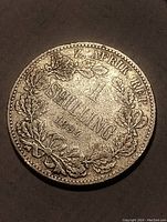 Close-up photo of the silver coin showing the year 1894, denomination 1 Shilling and wreath design.