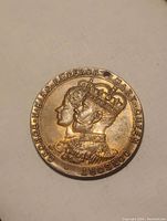 Obverse side showing the raised profile busts of King George V and Queen Mary with text around the border.