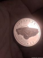 Copper coin token held in hand showing engraved 1959 Corvette convertible with 'CORVETTE' and '1959' text.