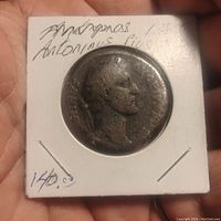 Obverse side of the coin showing a left-facing profile of Antoninus Pius and inscription handwritten on the holder.