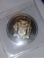 Obverse side of the proof silver Jamaican coin showing coat of arms and year 1971 in plastic holder.