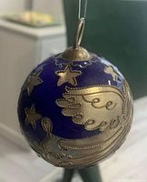 Front view showing deep blue glass surface with gold star and angel wing design and silver hanging loop