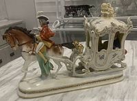 Front side view of the porcelain figurine showing horse, coachman, and carriage detailing.