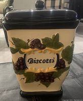 Front view of the ceramic biscotti jar showing hand painted grape and leaf design with 'Biscotti' label.