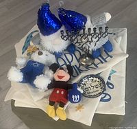 Lot items arranged on floor showing four pillowcases, two plush toys, menorah, and Shalom dish