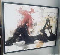 Framed wall art with black silhouette playing a trumpet and abstract paint splashes