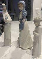 Three Lladro figurines standing together on a white surface, showing full front view for size and detail comparison.