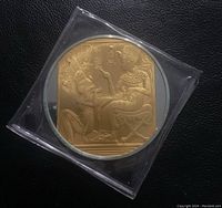 Front of coin showing detailed gold-highlighted Egyptian figures and hieroglyphics.