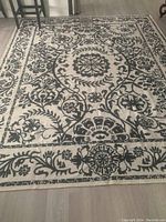 Rug laid flat showing full beige and gray floral medallion pattern