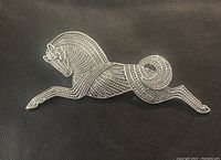 Image showing front view of the pewter-tone stallion horse brooch with detailed embossed linear and dot pattern, on a black background.