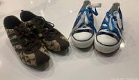 Two pairs of women’s size 10M sneakers, one Coach brown monogram and one blue high-top with Toronto Blue Jays logo