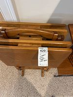 Top view of four wooden tray tables held together in the wooden holder. Shows trays stacked vertically.