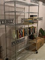 Full view of the metal shelving unit loaded with books for staging showing five wire shelves and wheels at the bottom.