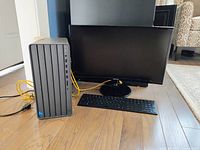 Front view of Samsung monitor, HP Intel PC, and HP wireless keyboard arranged on the floor with visible yellow cables behind.