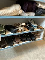 Shelves with multiple pairs of women's sandals and flip flops in neutral colors and various styles including platforms and flat soles
