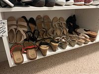 Multiple pairs of women's summer sandals in a closet shelf showing different styles and colors in lightly used condition
