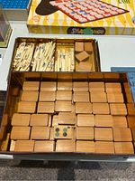 Top view of the Mahjong game box with bamboo tiles organized in rows along with one tile showing symbols and dots and wooden racks.