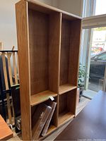 Front view of solid wood tall bookcase showing multiple compartments and removable shelves.
