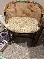 Vintage cane chair with cane woven barrel back and floral seat cushion.
