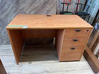 Full view of the wooden desk showing flat surface and three drawers on the right.