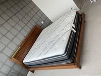 Angled view of assembled bed frame and mattress in carpeted room