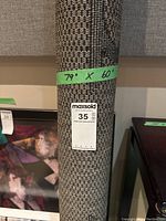 Rolled outdoor area rug with green tape showing dimensions 79" x 60"