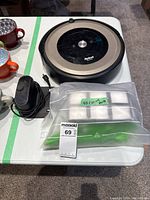 Robot vacuum, charging dock, adapter and sealed bag of replacement parts on table