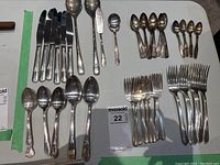 Full view of silverware spread on table showing knives, spoons, forks, and serving utensils.