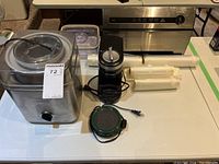 Wide shot of lot items on table showing all components including the frozen yogurt maker, food sealer, sealing films, and hot plate.