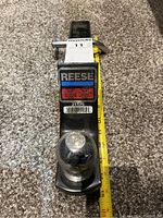 Front view of Reese tow hitch resting on carpet with measuring tape showing length of hitch