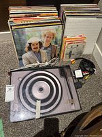 Front view of turntable dust cover and stacks of vinyl records arranged behind