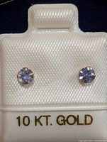Pair of 10K yellow gold tanzanite stud earrings in white holder labeled 10 KT. GOLD