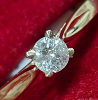Close-up of ring head showing round brilliant diamond in six-prong setting on yellow gold band