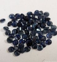 Multiple loose blue sapphire stones showing rounded faceted cut tops and polished bottoms.