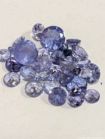 Close-up image showing a collection of loose round faceted tanzanite stones of varying sizes and blues hues.
